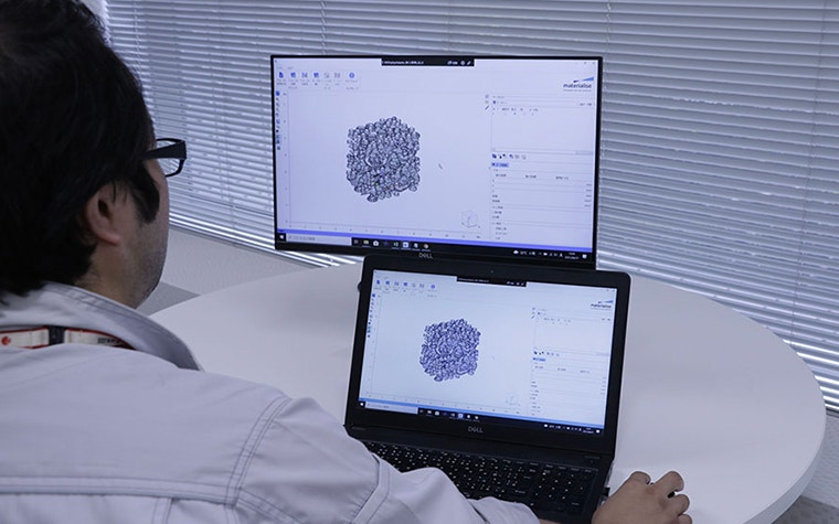 A SOLIZE employee in front of a computer screen showing parts being placed in Materialise Magics