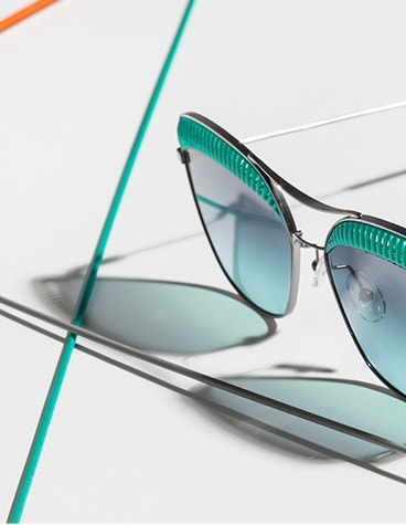 Angled view of sunglasses from the Safile Oxydo eyewear collection with a blue/green design on the top of the frame