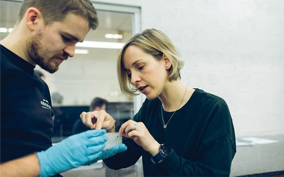 Two people checking a 3D-printed part in a production facility