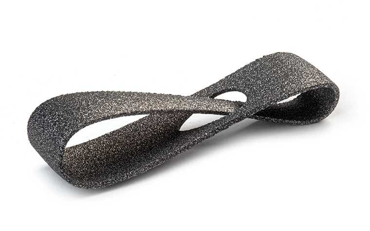 A glittering black 3D-printed loop made from PA-AF (aluminum filled) using laser sintering, with a color-dyed finish.