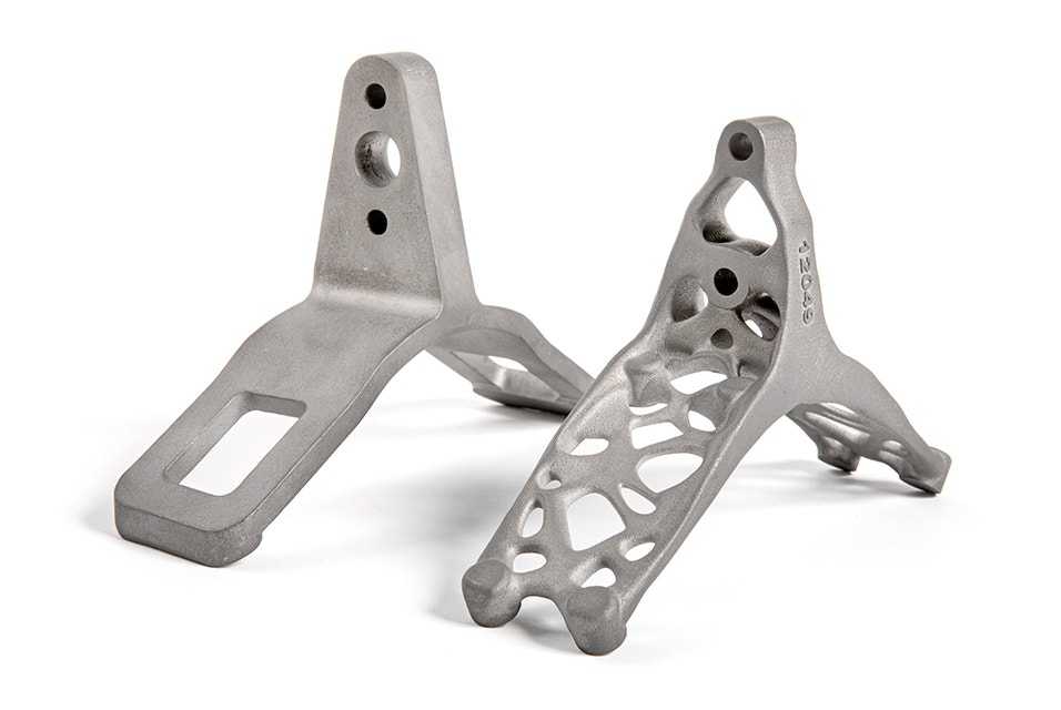 Side-by-side comparison of 3D-printed titanium lift brackets. One is solid and the other has an optimized design with holes