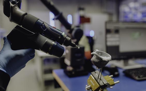 Gloved hand using a tool to optically scan a medical implant for a quality assessment