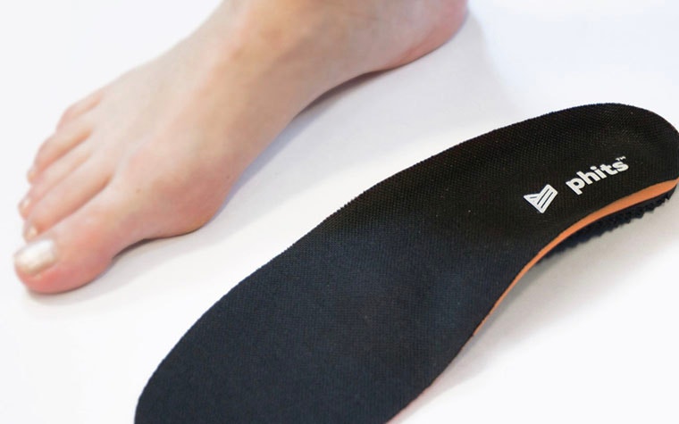 Bare right foot next to a 3D-printed phits insole with a cloth top