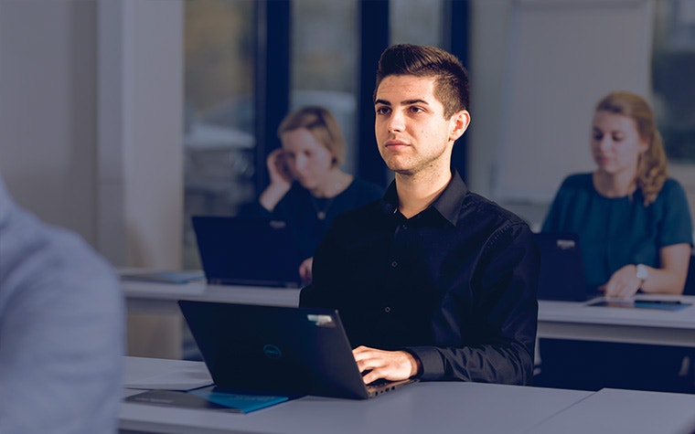 A group of three people with the laptops looking up at the teacher.