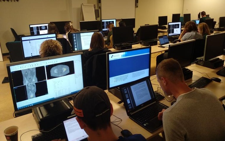 Students work on laptops in front of computer screens showing 3D images of bones