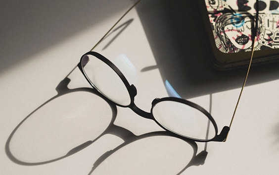 Eyeglasses laying on a design with its shadow extended