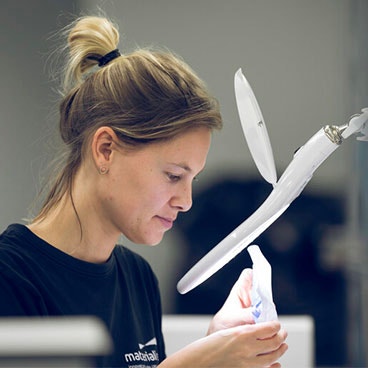 Woman observing a 3D-printed part under a light