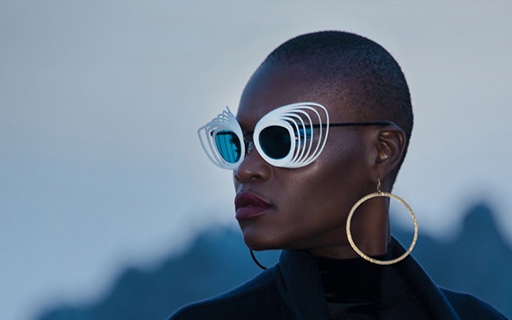 Black female model wearing white, geometric JF Rey sunglasses and looking off into the distance