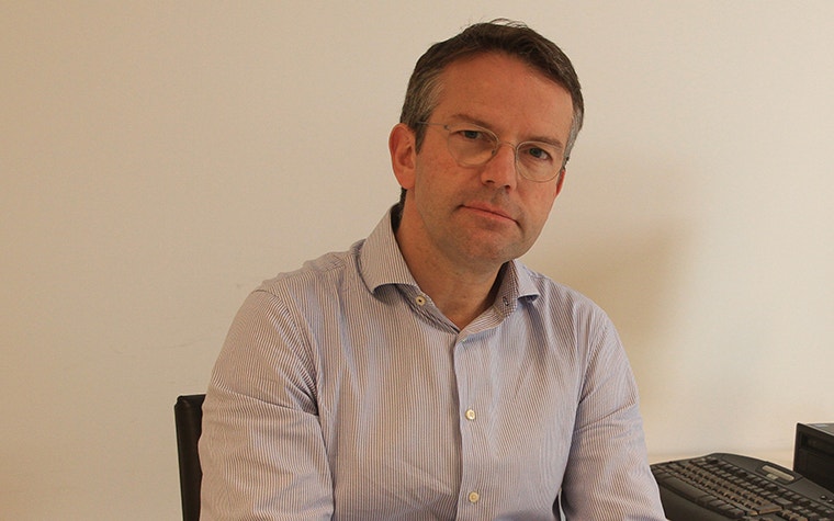 Dr. Frederik Verstreken at a desk holding a 3D-printed anatomical model 