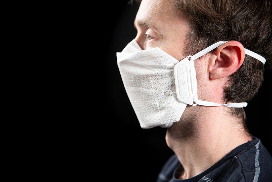 Seitenansicht eines Mannes mit einer Maske aus Stoff, Gummiband und 3D-gedruckten Clips