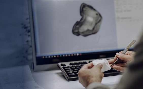 컴퓨터의 3D 디자인 앞에서 3D 프린팅된 해부학 모형을 들고 있는 손