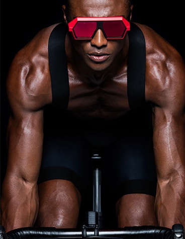 Modèle masculin noir sur un vélo, portant des lunettes rouges de VAVA Red Label.