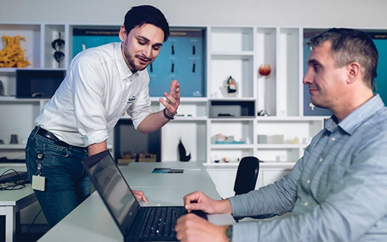 Instructor explaining something to a student at his computer