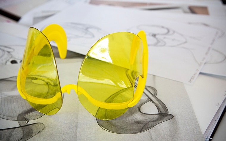 Yellow 3D-printed sunglasses designed by David Ring, sitting on top of his drawings