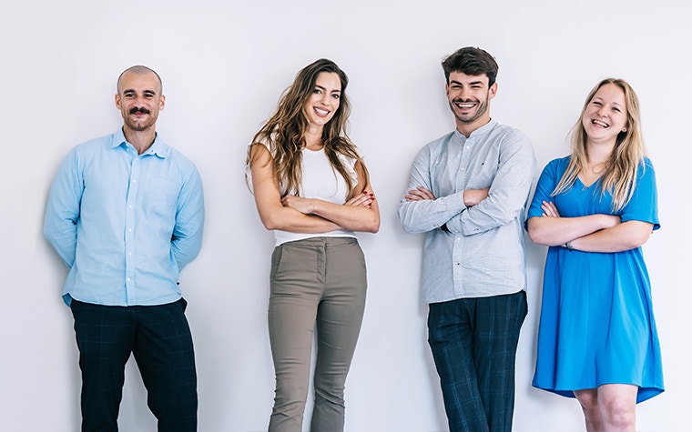 Group of four professionals stannding next to each other and smiling while looking into the camera