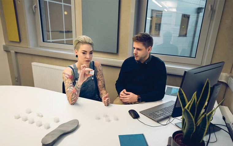 Materialise employees looking at a 3D-printed cube