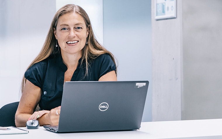 Woman sitting at a table in front of a laptop and smiling