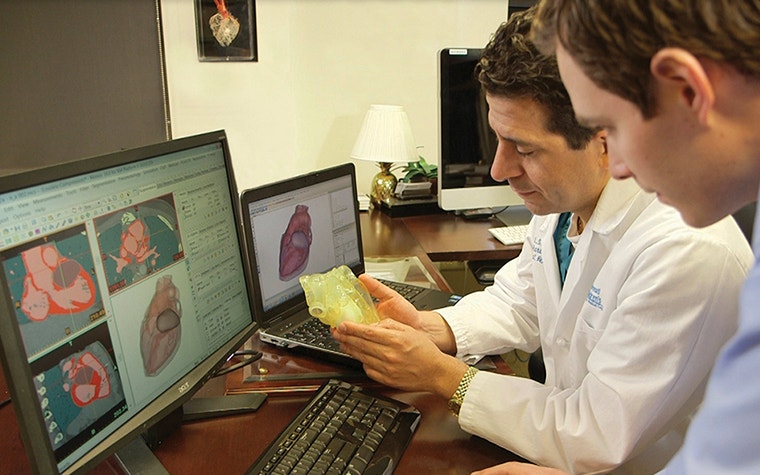 Doctor holding an anatomical model and reviewing digital scans 