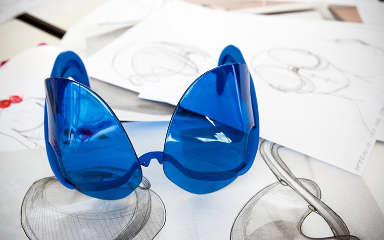 Blue 3D-printed sunglasses designed by David Ring, sitting on top of his drawings