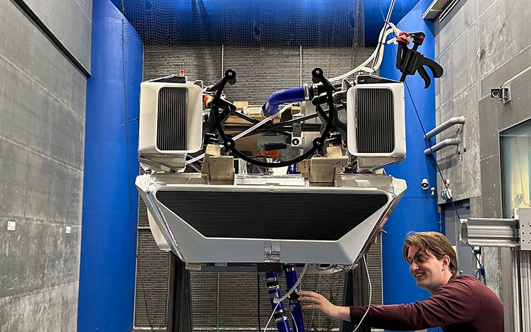 A TU Delft student stands next AeroDelft's 3D-printed air ducts for a Sling 4 kit aircraft retrofitted with a liquid hydrogen engine inside a wind tunnel.