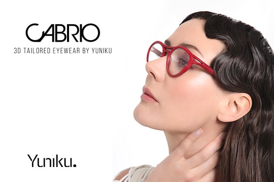 Modèle féminin aux cheveux ondulés autour du cou et levant les yeux, portant des lunettes rouges Yuniku Cabrio