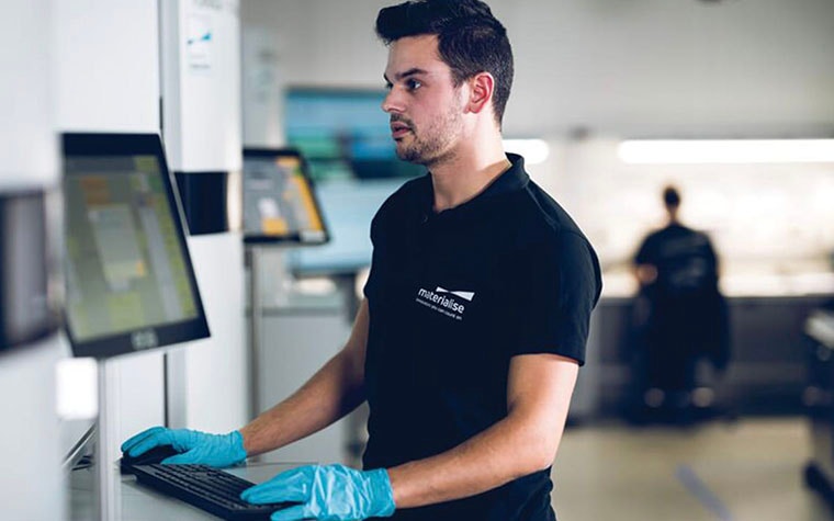 Man standing in a production facility, using a computer