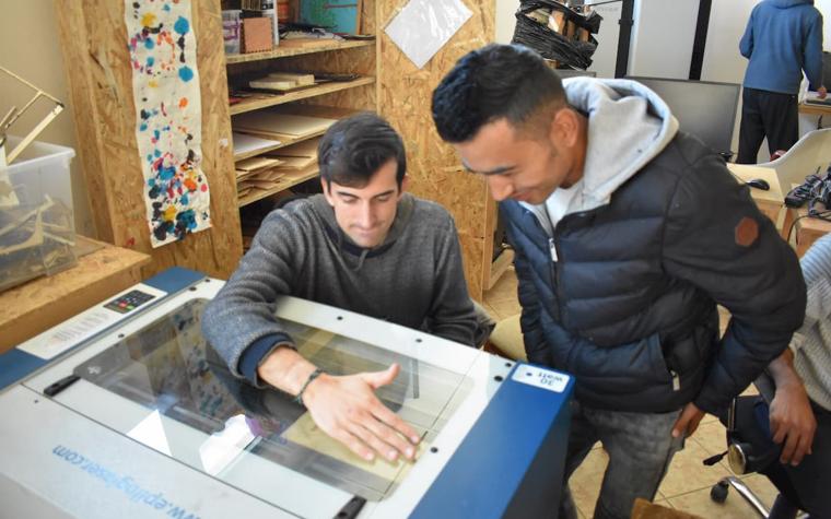 Two men using a laser cutting machine