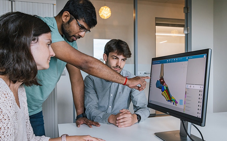 A group of people looking at a computer screen with a foot model in Mimics.