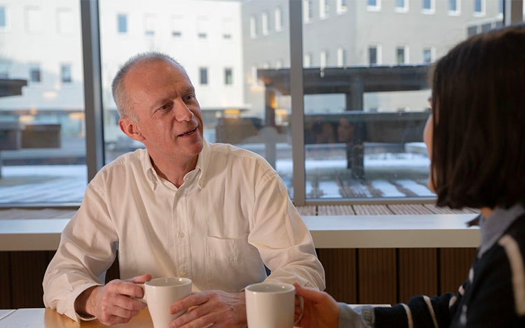 Quality Engineer Eddy Couvreur talking to a colleague while drinking coffee