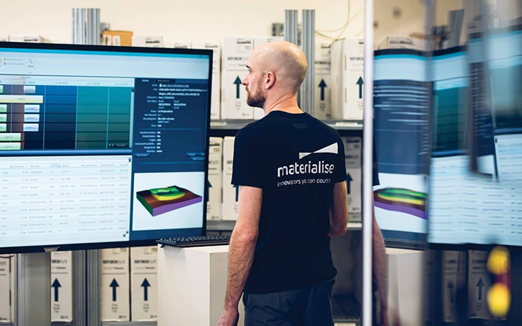 Materialise employee checking machine statuses on a large screen in production