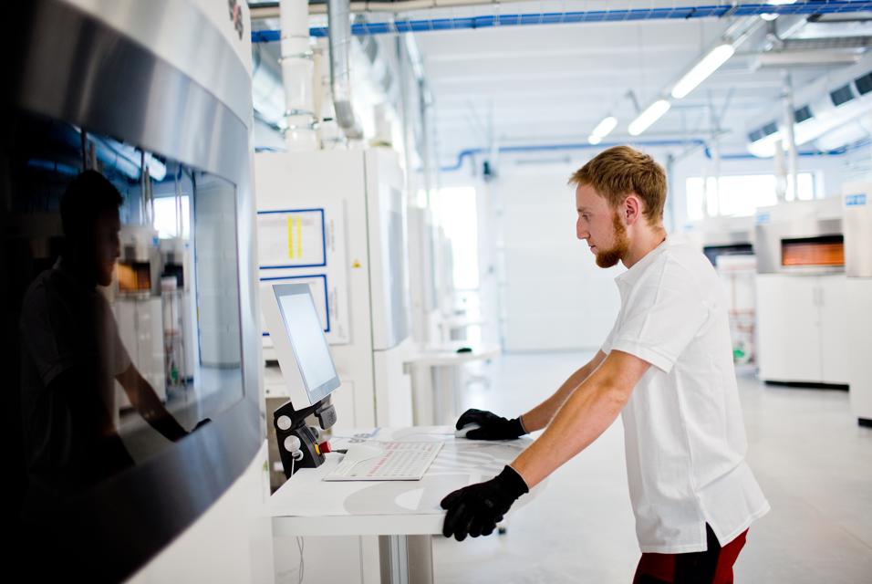 Uomo che usa un computer in uno stabilimento di produzione con stampa 3D