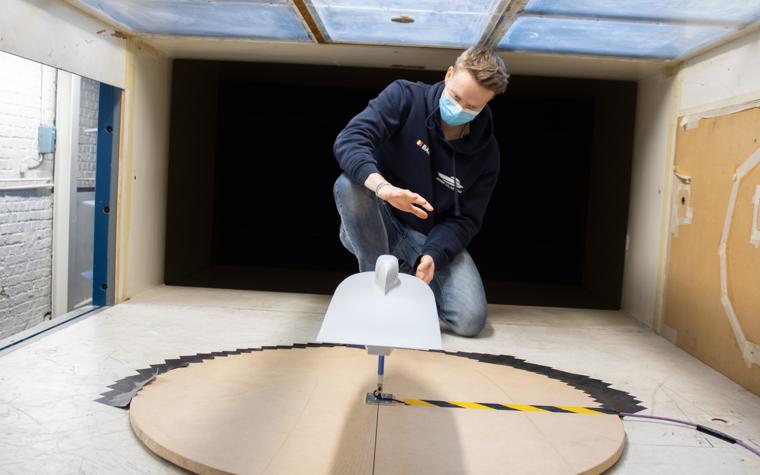 A student in the Agoria Solar Team adjusts the positioning of a 3D-printed replica of the Agoria Solar Car in a wind tunnel.