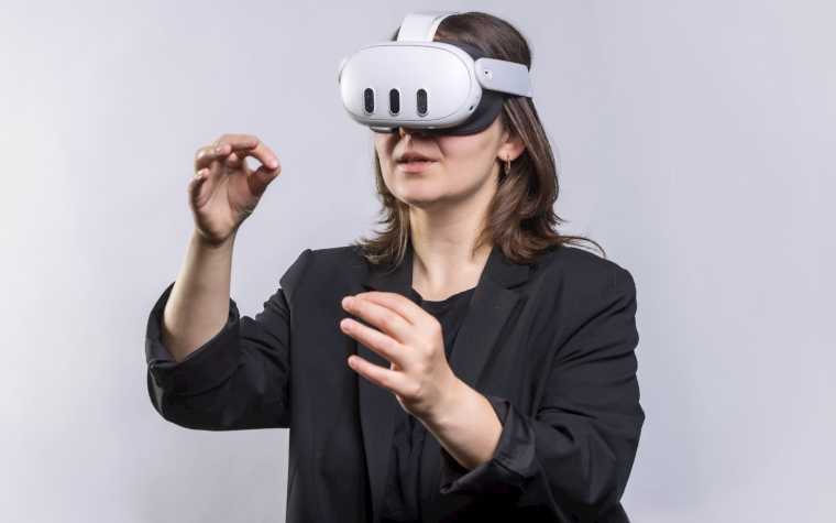 A woman wearing the Meta Quest 3 goggles with her hands in front of her