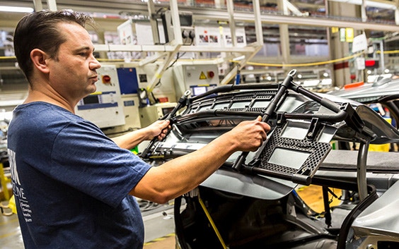 An engineer uses a 3D-printed jig to accurately place a car trunk lid.