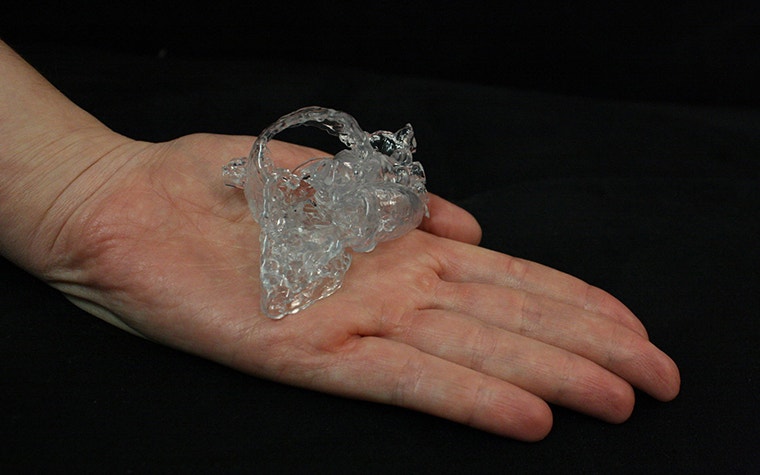 Modelo de corazón impreso en 3D sentado en la palma de una mano