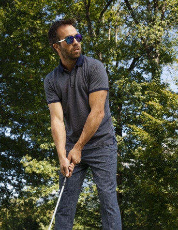 Homme tenant un club de golf et portant des lunettes de soleil McLaren Vision Openmatic