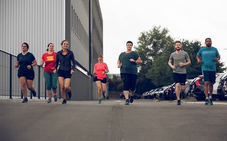 Group of Materialise employees running in a parking lot