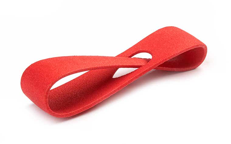 Eine rote 3D-gedruckte Schlaufe aus PA 12, die im Lasersinterverfahren hergestellt wurde, mit einer glatten und gefärbten Oberfläche.