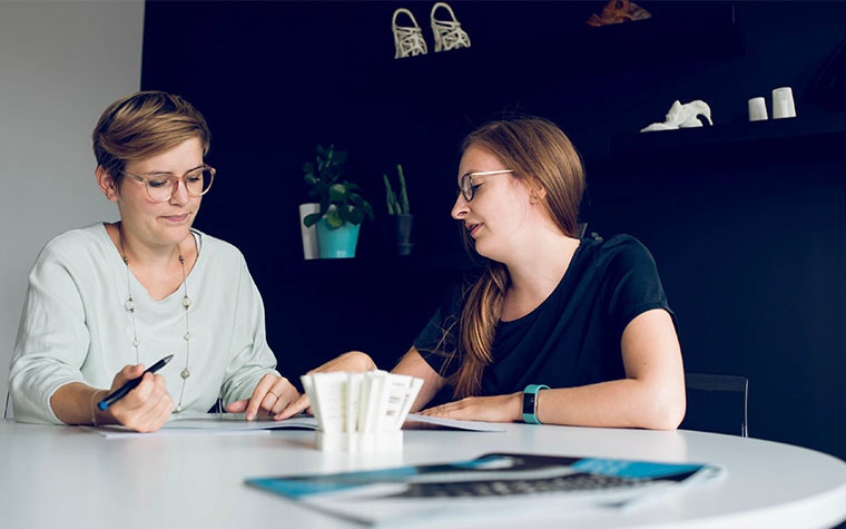 Two Materialise employees discussing paperwork at a table