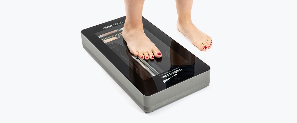 Person standing with one foot on the iQube E100 scanner and one foot on the ground