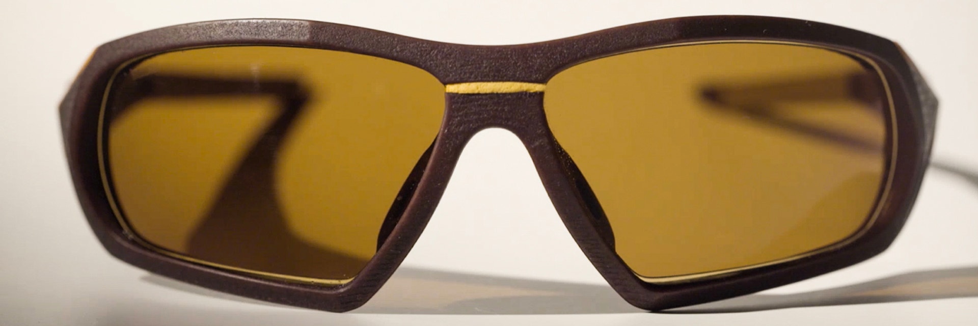 Pair of SEIKO Xchanger 3D-printed sports glasses with brown frame, yellow accents, and smoke-tinted lenses, seen from front 