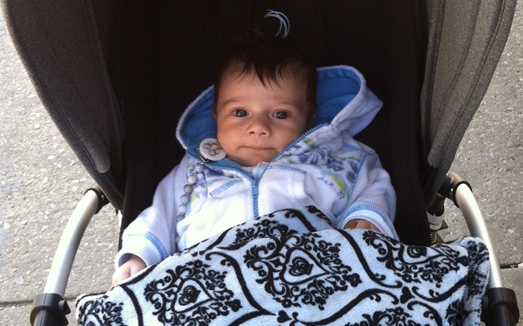 Baby wearing blue coat sitting in a stroller 