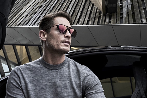 Man standing outside, looking off to the side, while wearing McLaren sunglasses
