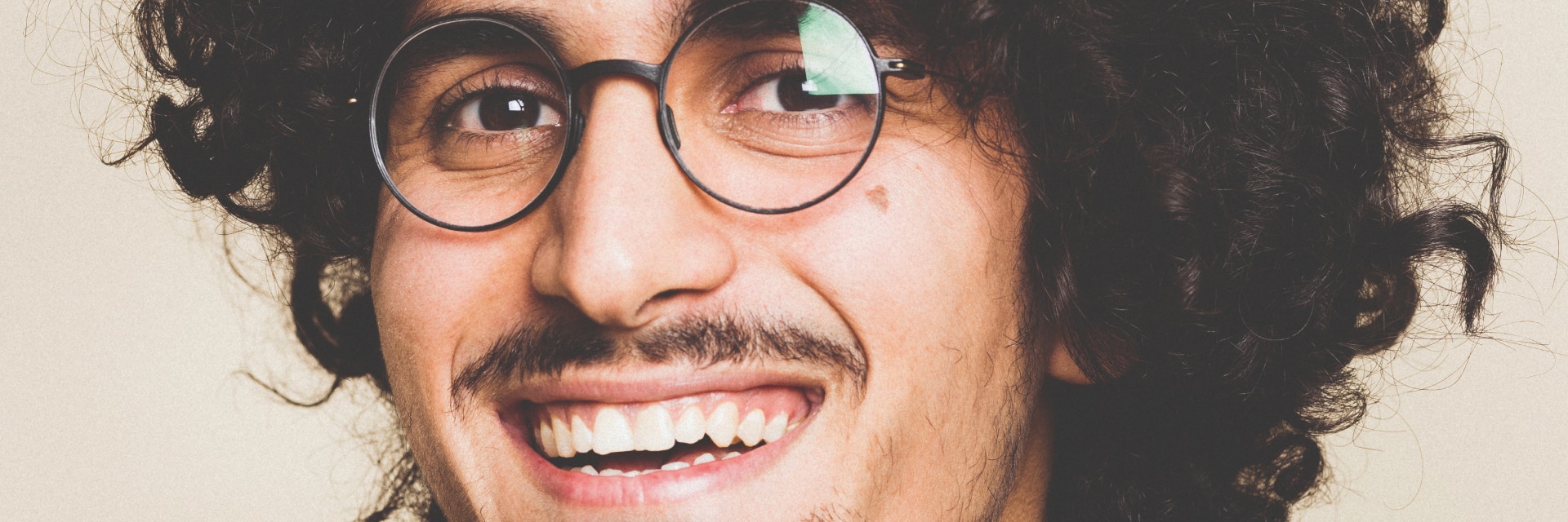 Lächelnder Mann mit lockigem Haar und Schnurrbart, während er eine 3D-gedruckte Weareannu-Brille trägt