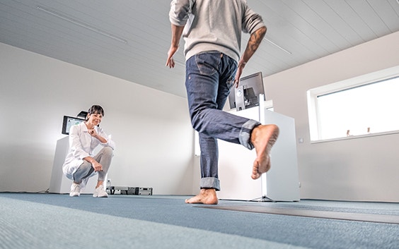 Doctor crouching down to observe a patient running on a footscan