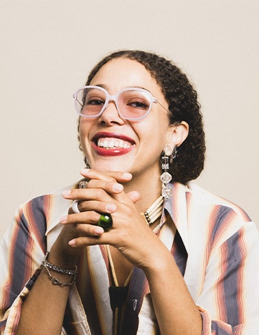 Woman smiling with her hands clasped under her chin, wearing weareannu's 3D-printed Square 17 m eyewear frames