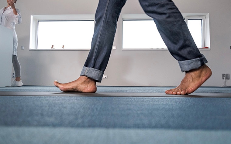 Person in cuffed jeans walking barefoot along a pressure plate