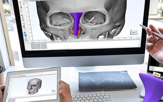Person looking at skull anatomy on a computer next to a person looking at the software on a tablet