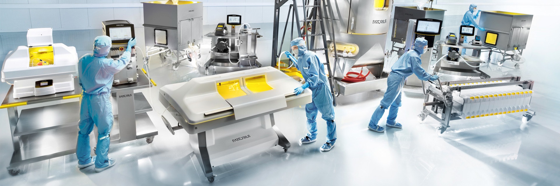 Sartorius employees in protective gear work with medtech machinery.
