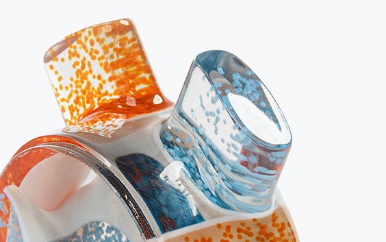 Obenaufnahme eines 3D-gedruckten statischen Mischers, größtenteils transparent mit einigen orangen und blauen Partikeln im Inneren